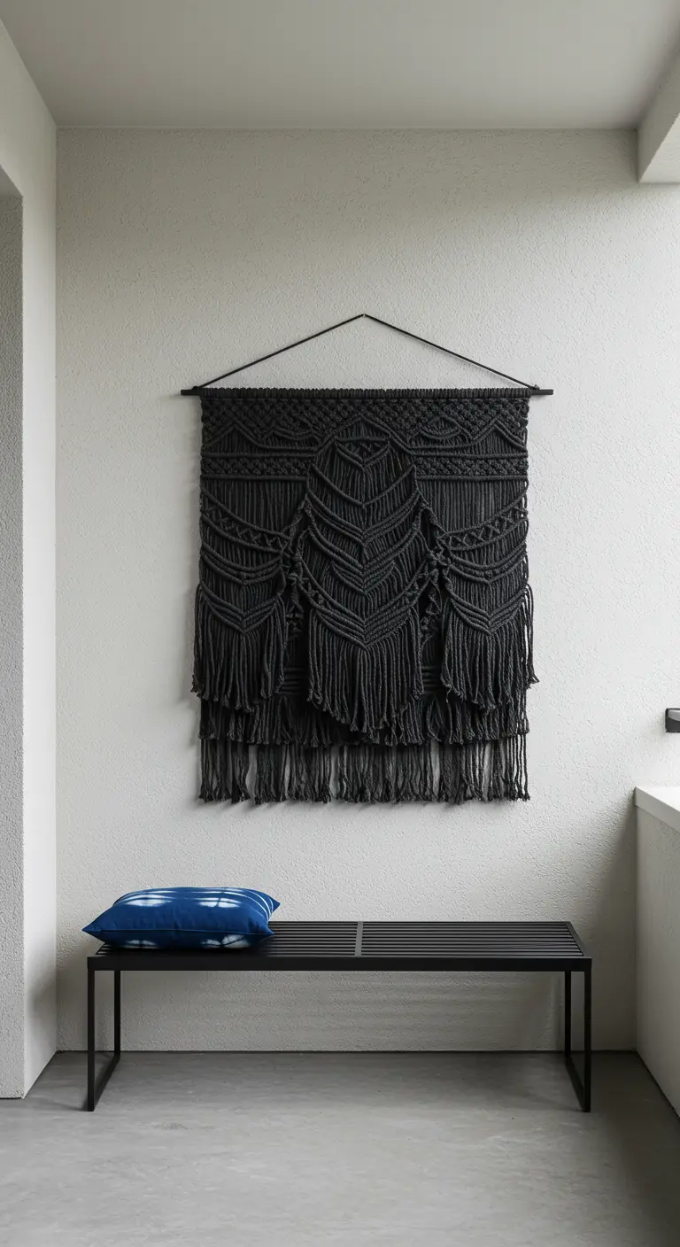 Balcón minimalista con un tapiz de macramé negro sobre un banco de metal negro.