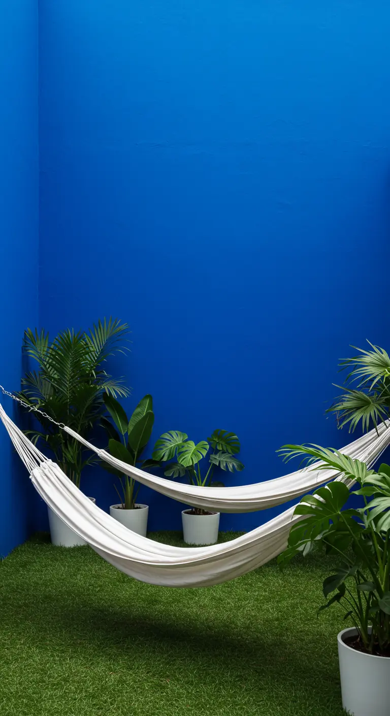 Patio con una pared azul intenso, dos hamacas blancas y plantas en macetas blancas.