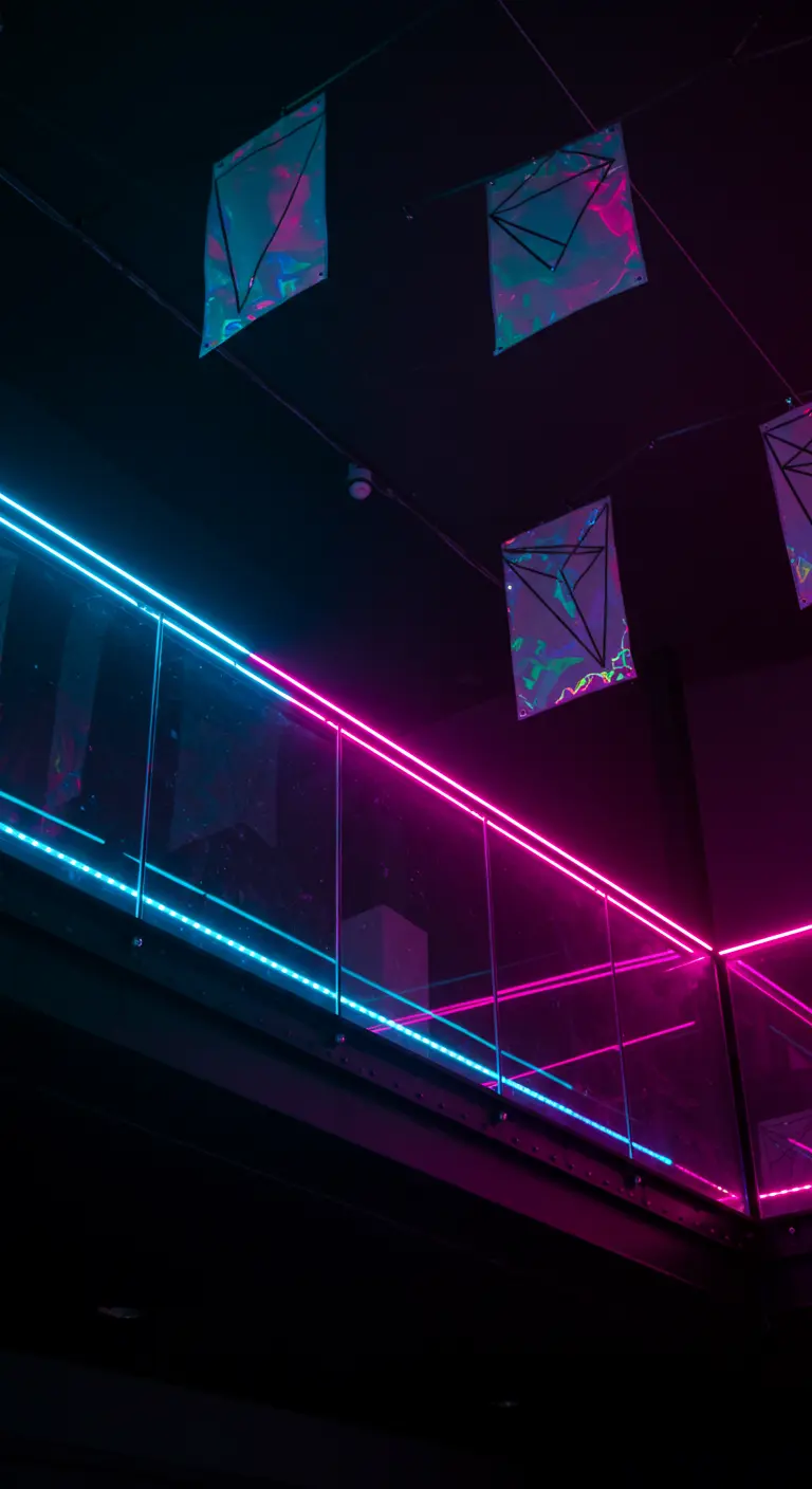Balcón oscuro con barandilla de cristal iluminada por tiras de neón azul y rosa.