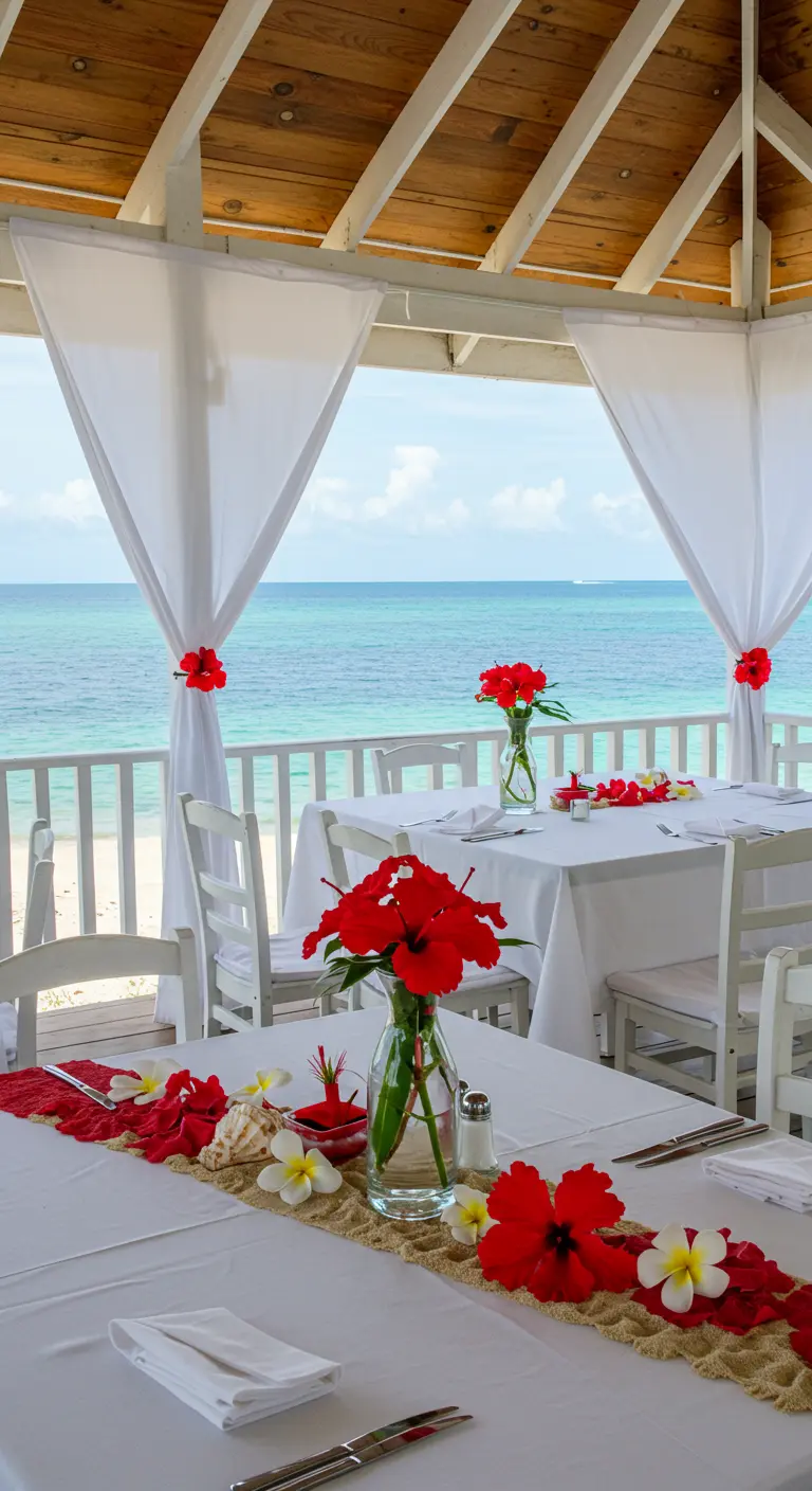 Mesa junto al mar decorada con flores de hibisco rojo y detalles playeros.