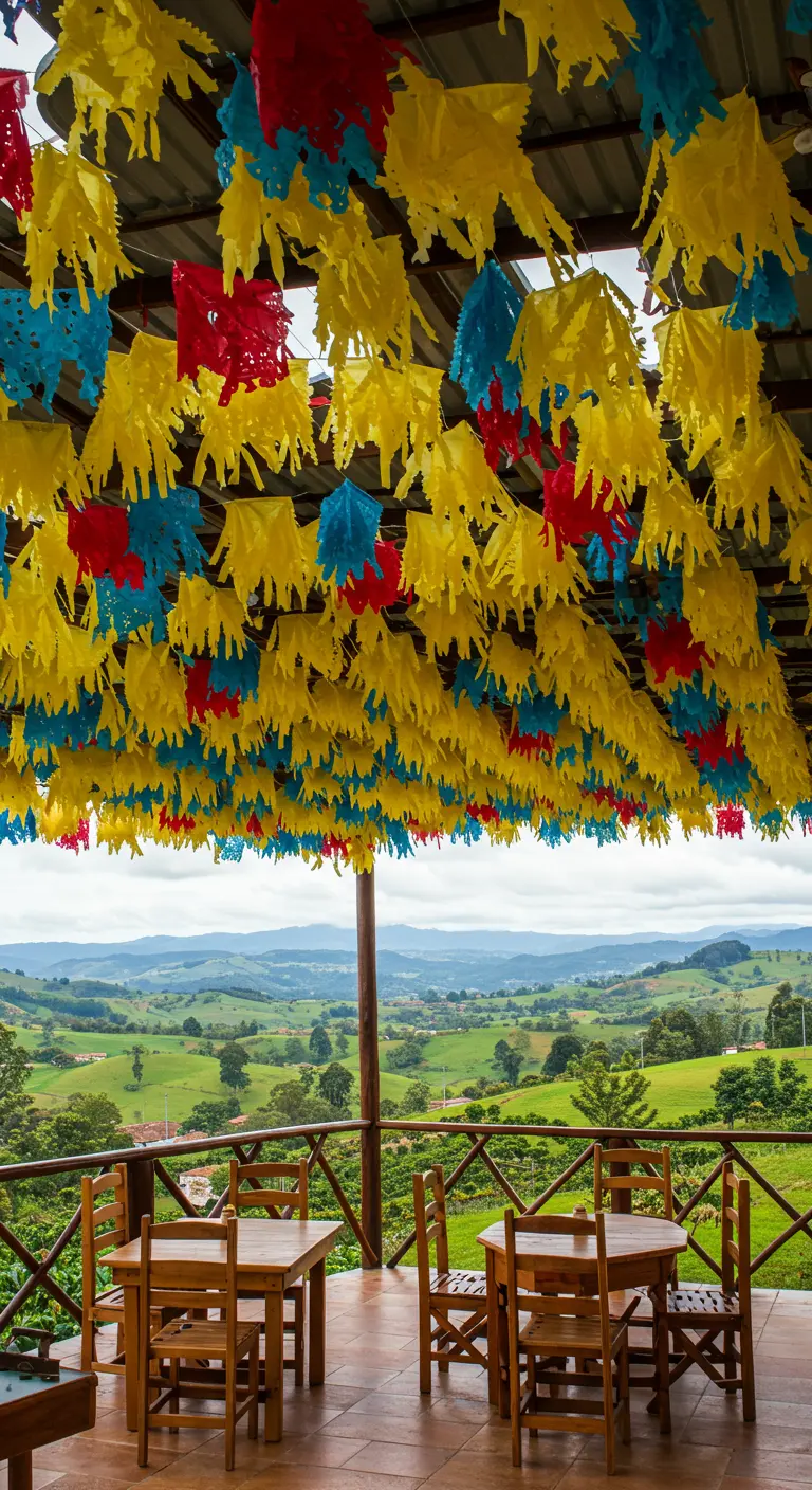 Balcón con vistas a un paisaje verde, con un techo cubierto de guirnaldas de flecos amarillas, azules y rojas.