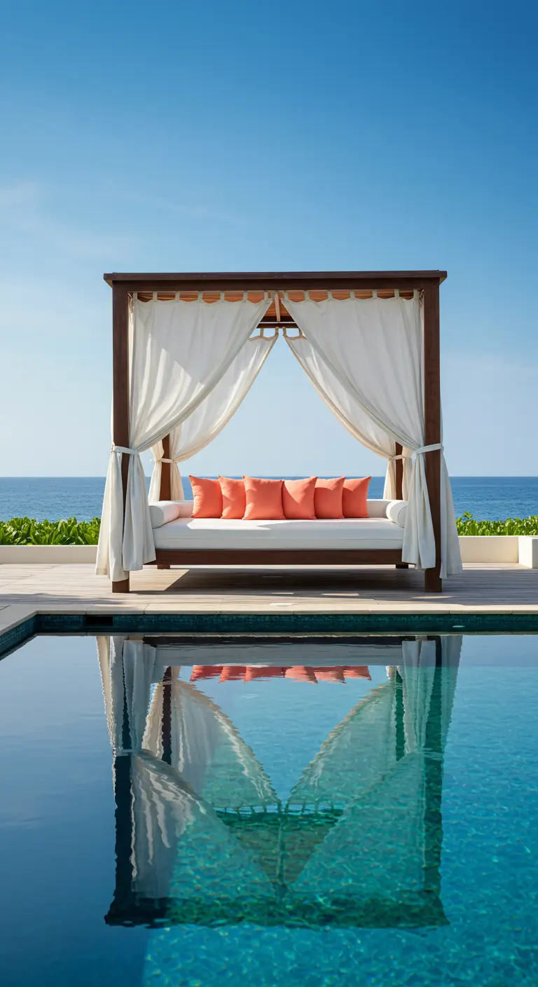 Cama balinesa de madera oscura con cortinas blancas y cojines naranjas junto a una piscina.