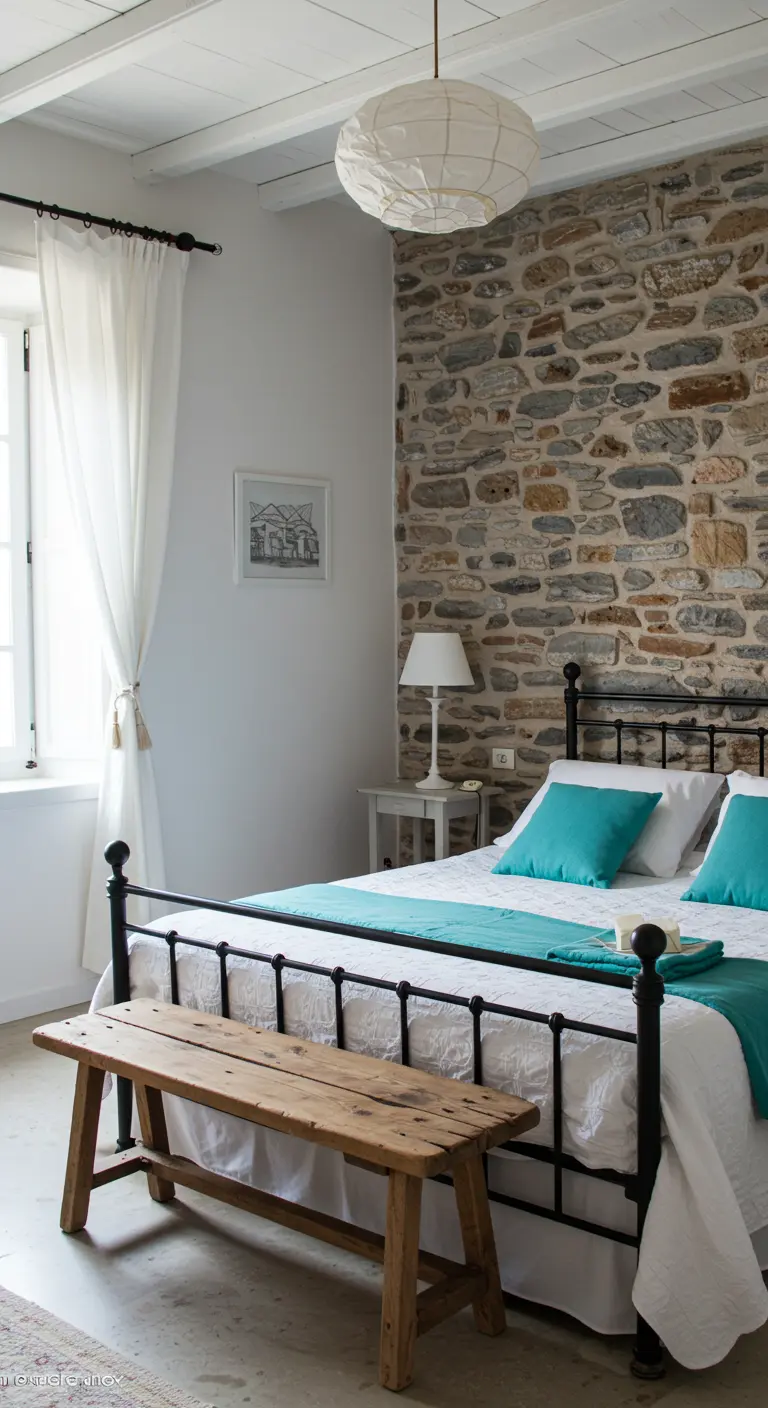 Dormitorio rústico con pared de piedra, cama de hierro forjado y detalles en turquesa.