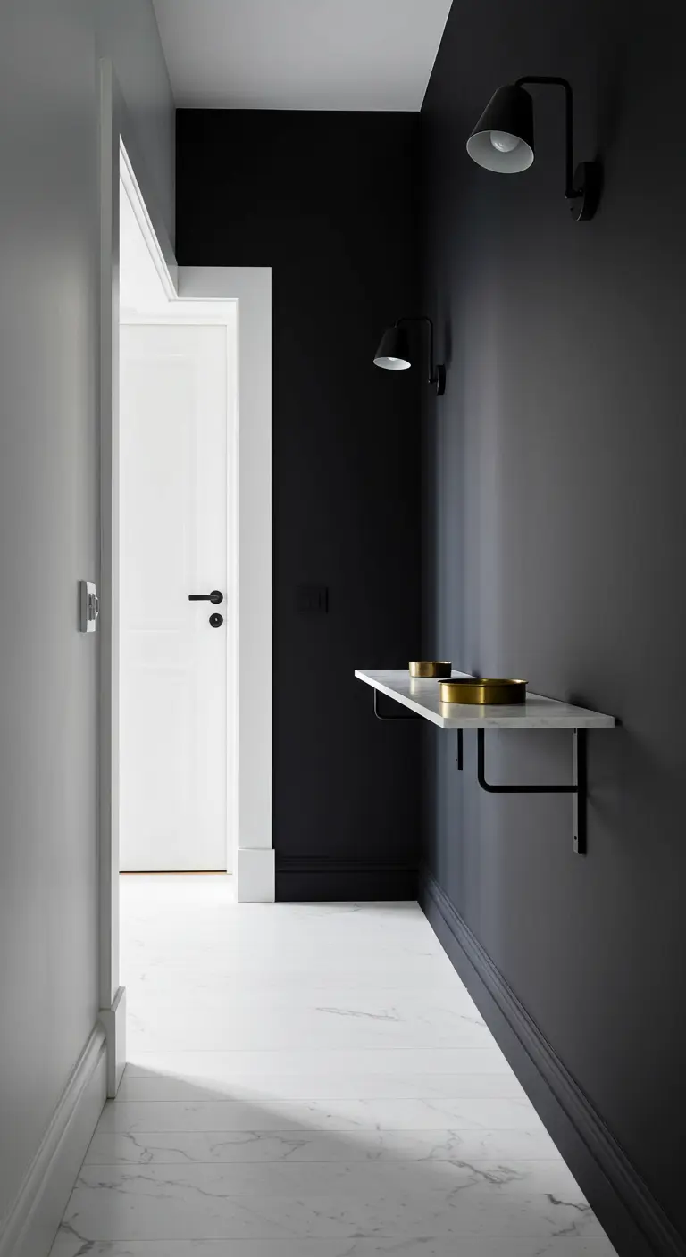 Pasillo estrecho con pared negra, suelo de mármol blanco y una pequeña consola de mármol.