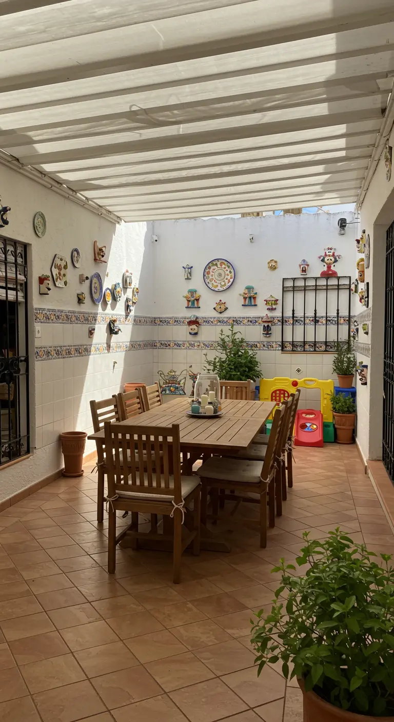 Patio familiar con una gran mesa de madera, paredes blancas con platos de colores y juguetes