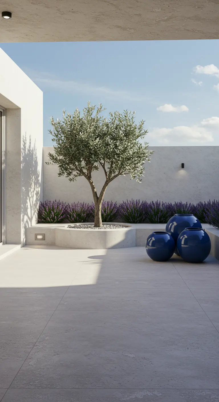 Patio minimalista con un olivo joven, lavanda y tres macetas esféricas de color azul intenso