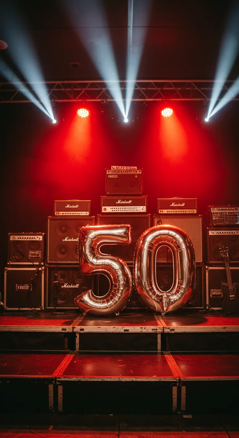 Globos plateados del número 50 en un escenario con amplificadores y luces de concierto rojas.