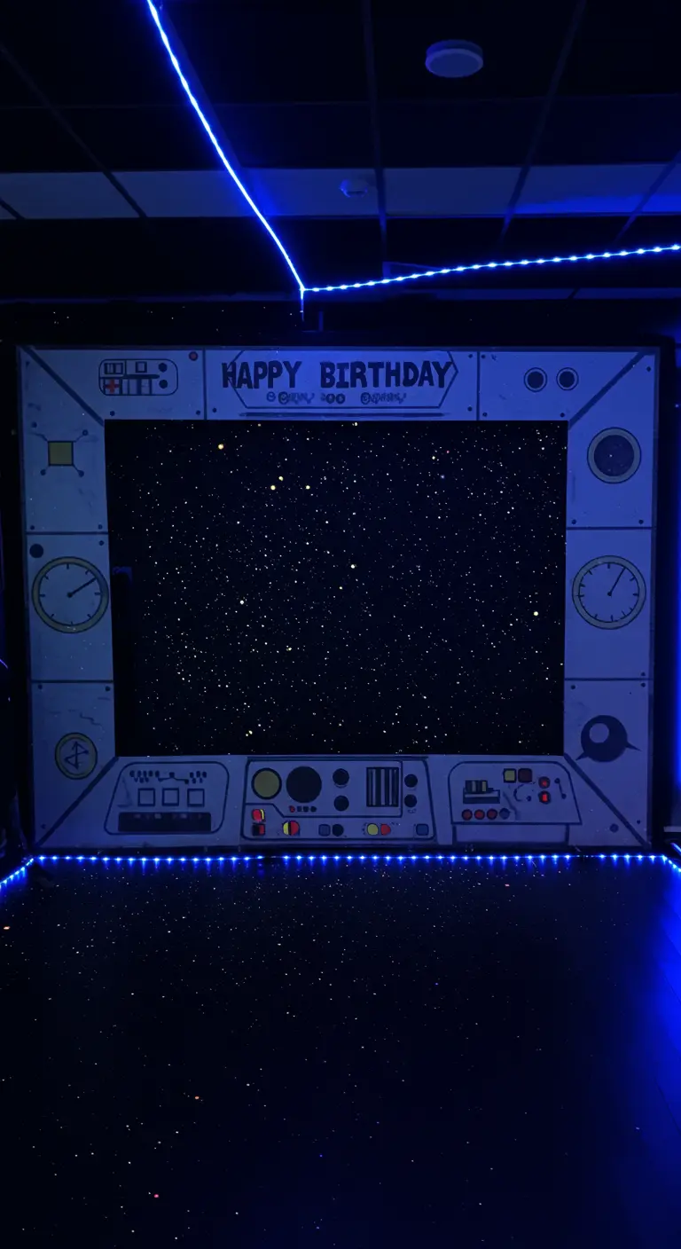 Photocall con forma de ventana de nave espacial y un fondo de estrellas con luces azules.