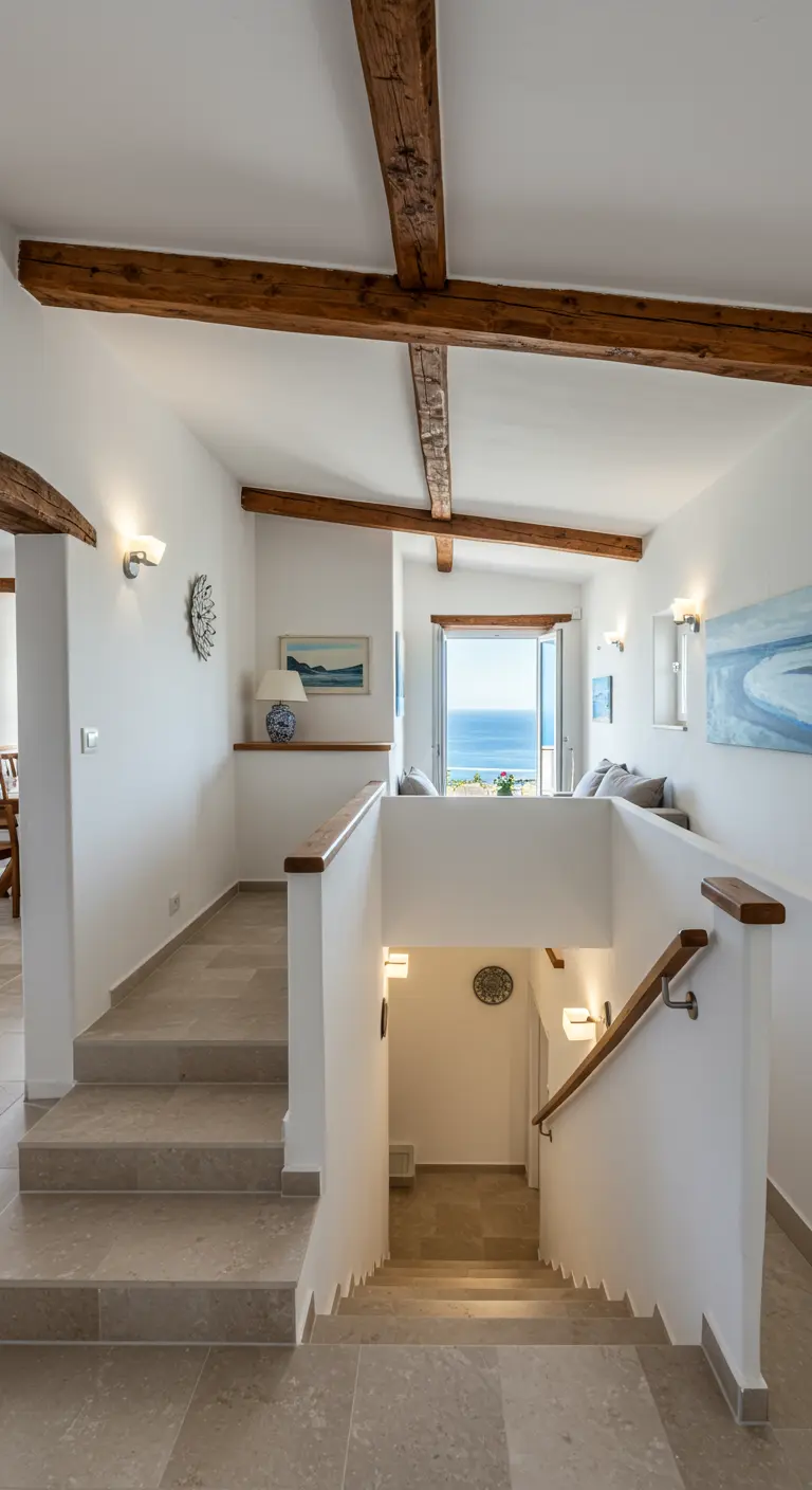 Entrada de varios niveles con vigas de madera, escaleras de piedra y vistas al mar.