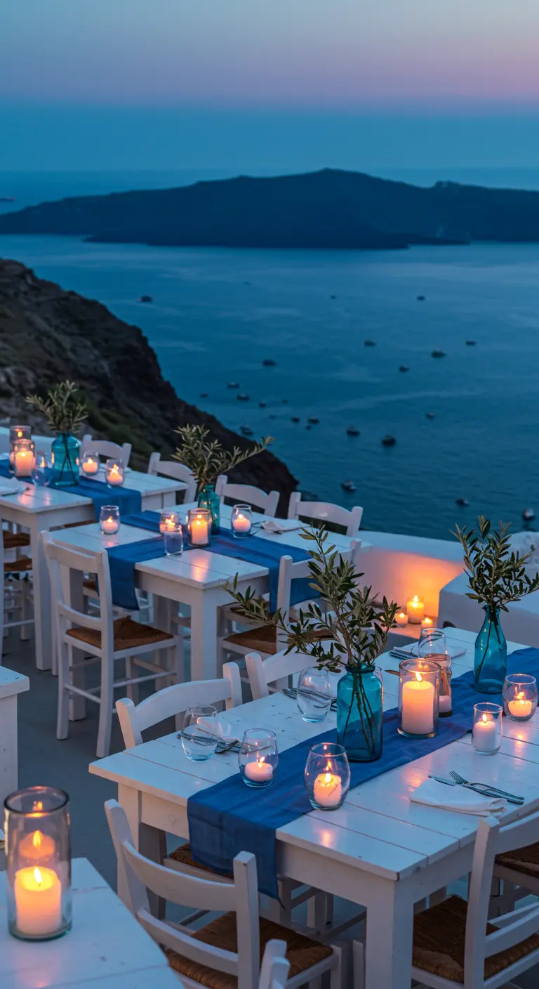 Mesas de restaurante en un acantilado griego, decoradas en blanco y azul con velas.