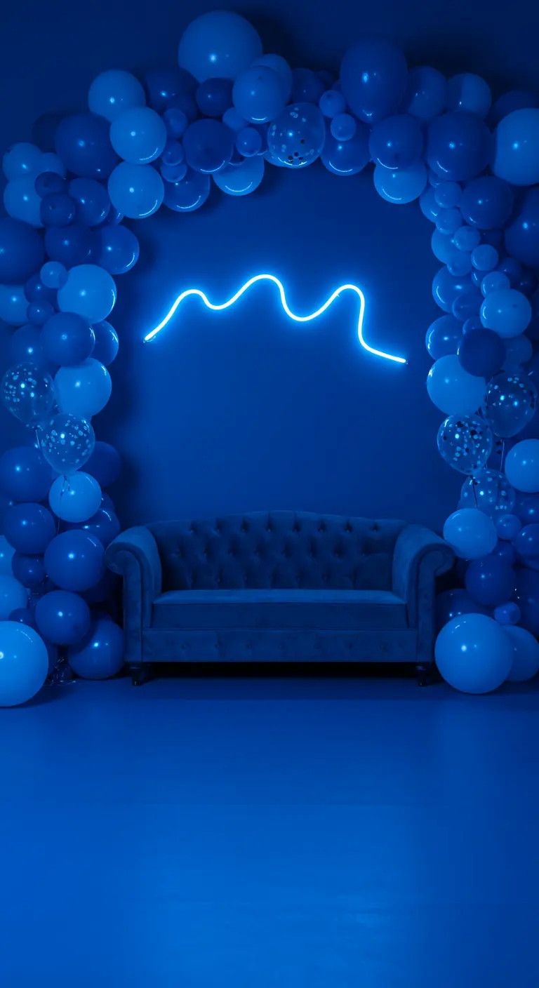 Espacio azul monocromático con un sofá y un arco de globos enmarcando un neón abstracto.
