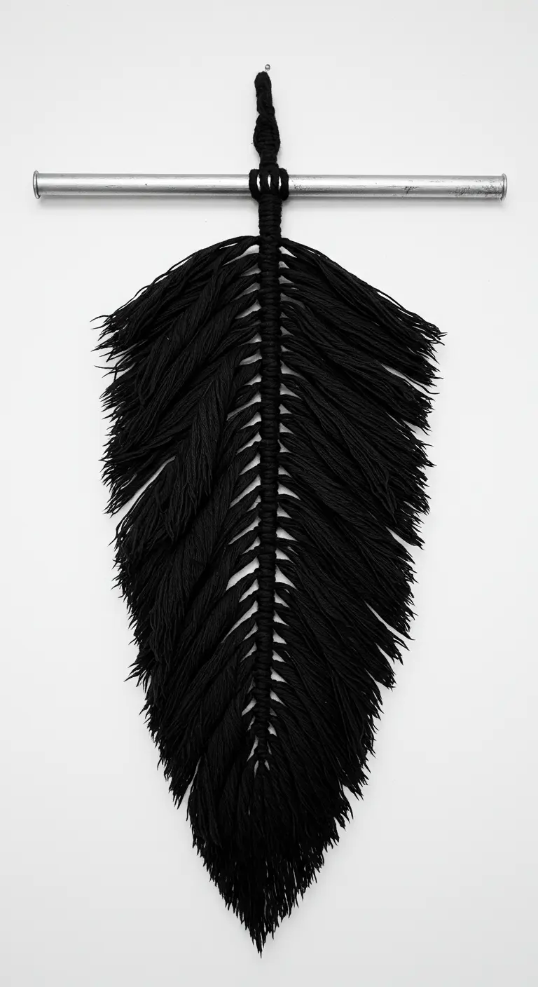 Una única y gran pluma de macramé negro colgada de una barra metálica