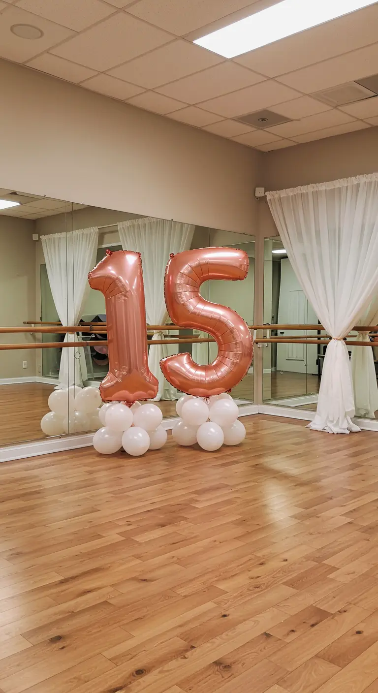 Globos oro rosa del número 15 en un estudio de danza con suelo de madera y espejos.