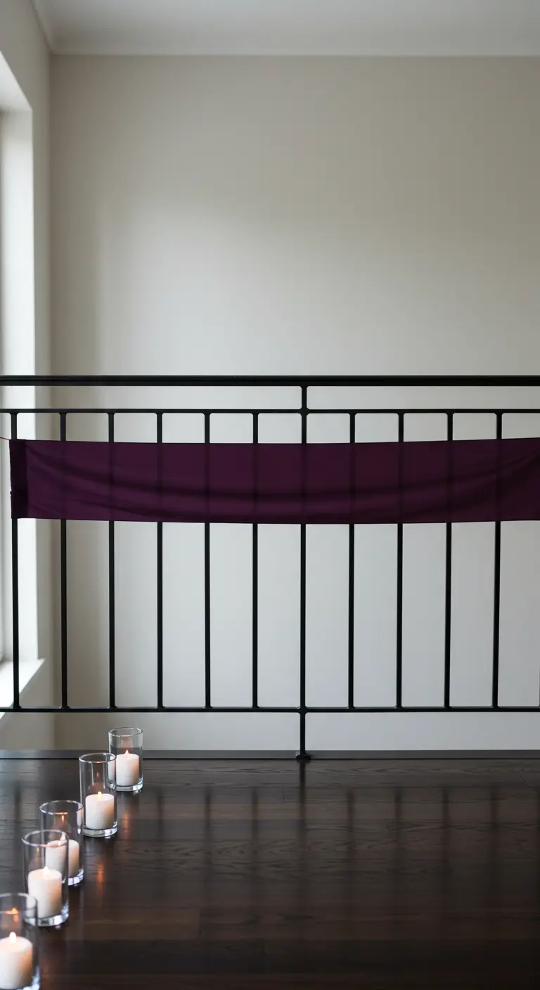 Barandilla interior negra con una tela morada y velas en vasos de cristal en el suelo.