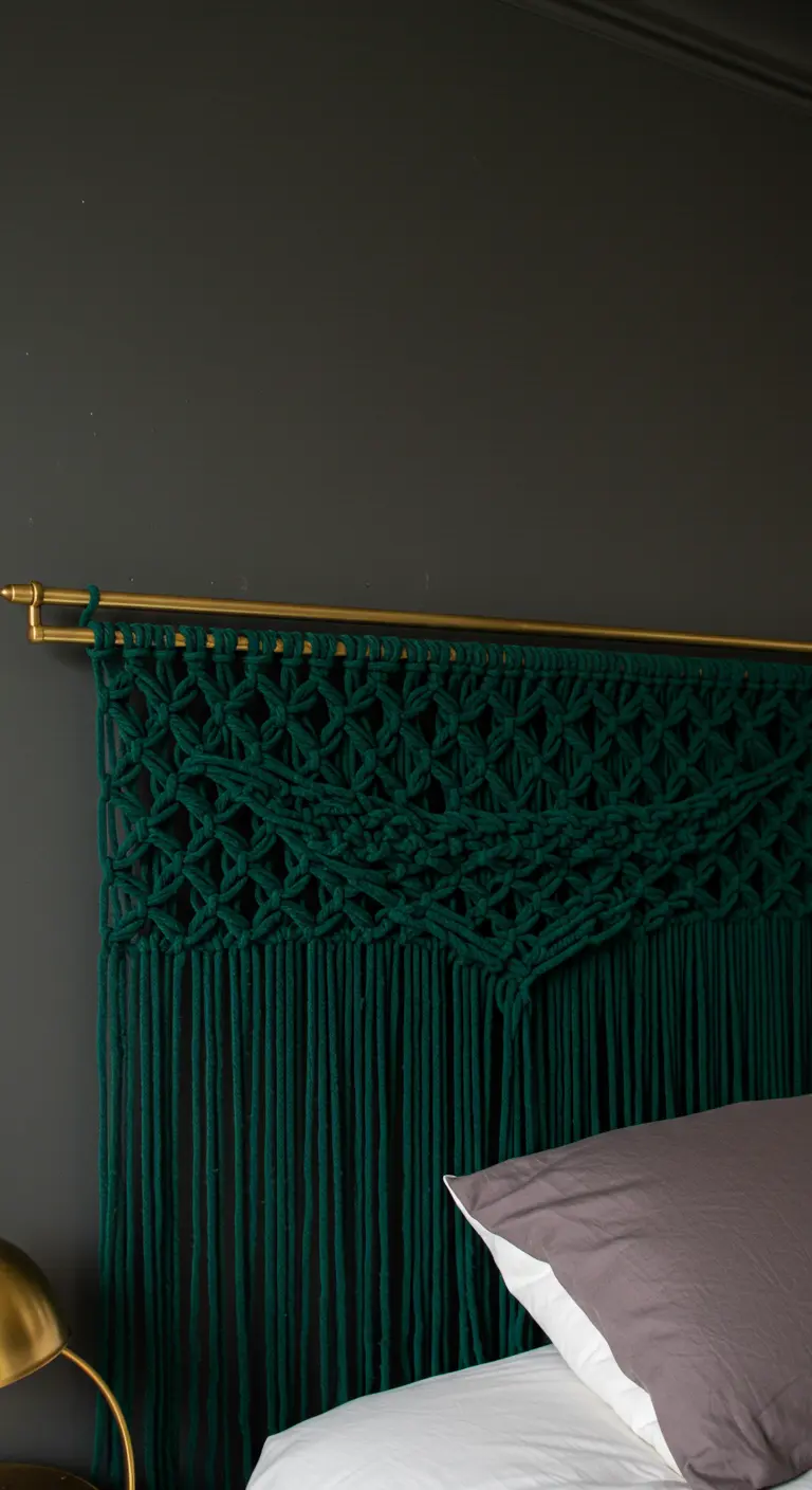 Cabecero de macramé de color verde esmeralda intenso colgado de una barra metálica dorada.