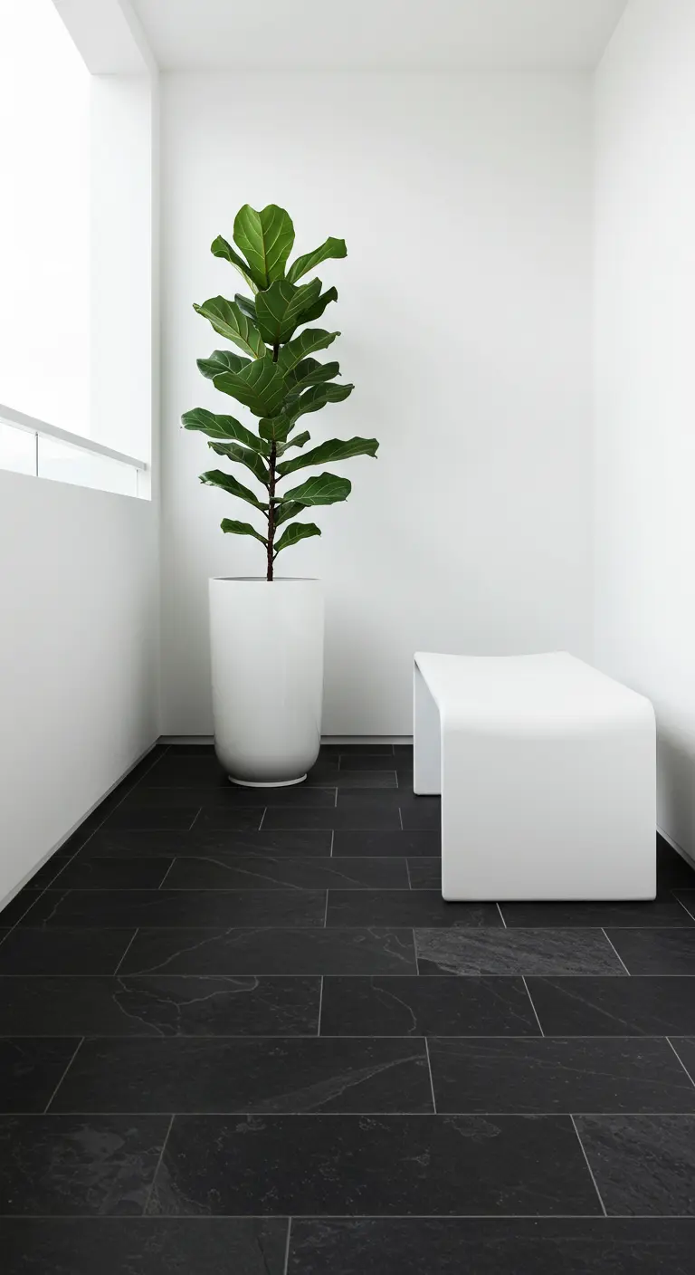 Rincón de balcón minimalista con paredes blancas, suelo de pizarra negra y un banco blanco escultural
